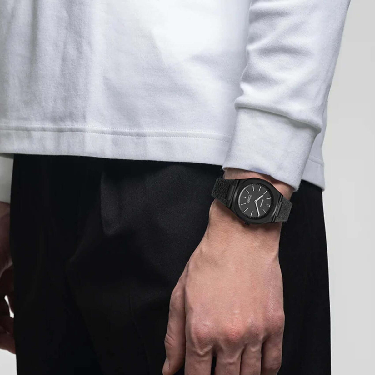 Φορεμένο ανδρικό ρολόι D1 Milano Black Kevlar D1-UHKJ01 σε ανδρικό χέρι με μαύρο λουράκι Kevlar.