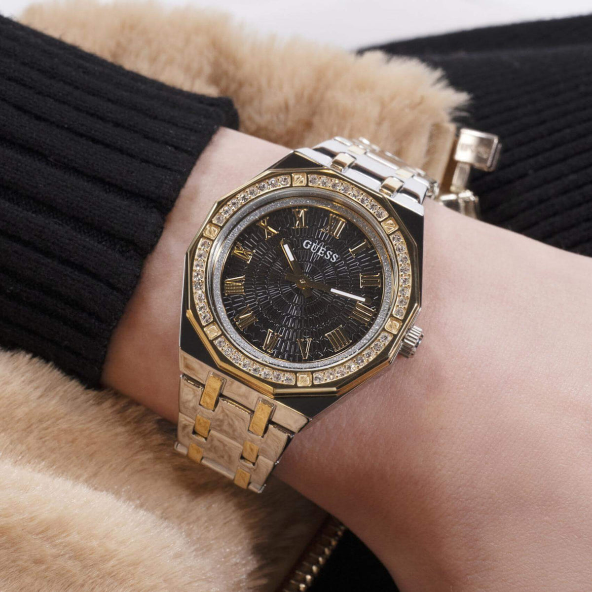 Γυναικείο ρολόι Guess Desire GW0770L4 φορεμένο με δίχρωμο ατσάλινο μπρασελέ σε ασημί και χρυσό χρώμα, μαύρο καντράν, χρυσές λεπτομέρειες και στεφάνη με ζιργκόν.