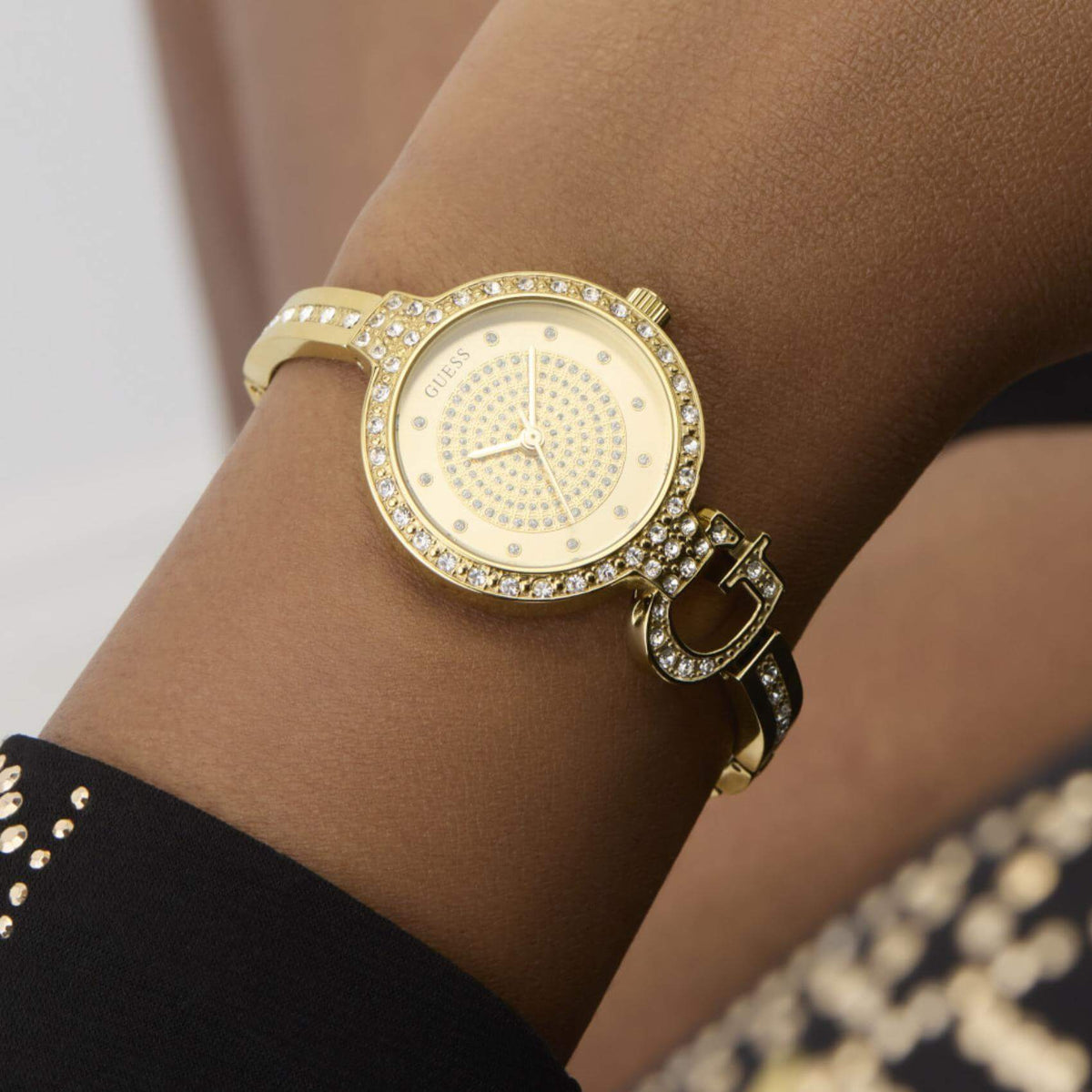 Γυναικείο ρολόι Guess Giselle GW0929L2 φορεμένο με χρυσό ατσάλινο μπρασελέ σε στυλ βραχιολιού, χρυσό καντράν και στεφάνη με ζιργκόν.