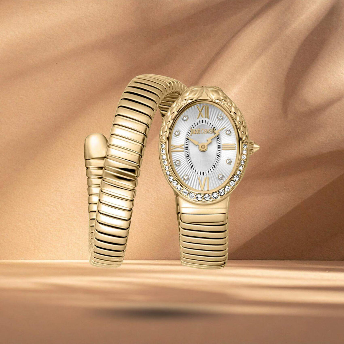 Just Cavalli JC1L390M0025 γυναικείο ρολόι με χρυσό ατσάλινο μπρασελέ, ασημί οβάλ καντράν μεγέθους 22x31mm και χρυσή στεφάνη με λαμπερά ζιργκόν και φίδι.
